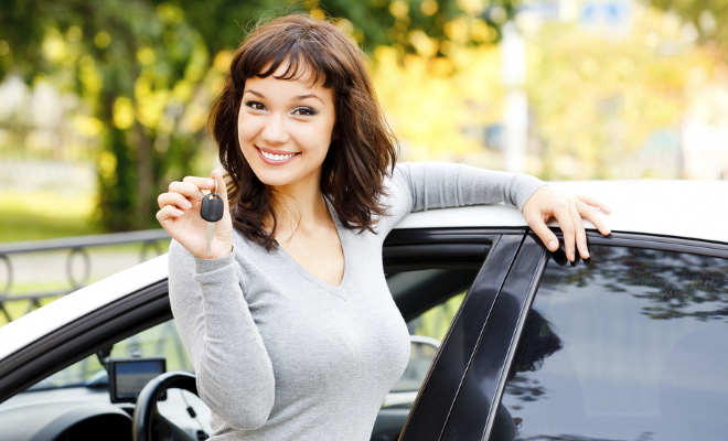 smiling woman holding keys to car